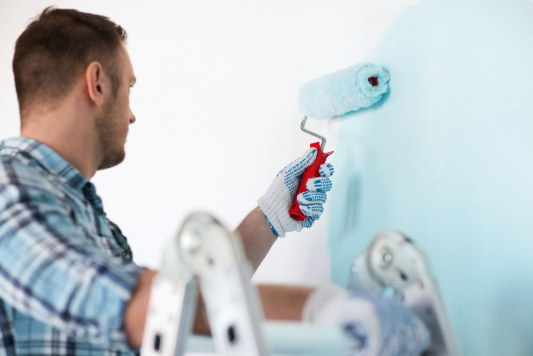 Maler streicht eine Wand mit der Farbrolle